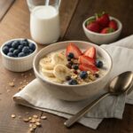 A bowl of creamy oatmeal topped with bananas, blueberries, strawberries, and chia seeds, served on a rustic wooden table.