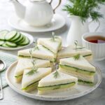 Cucumber sandwiches arranged on a tiered tray with tea set and scones, perfect for tea parties and light meals.