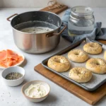 Homemade bagels in different stages: dough rings, boiling bagels, and freshly baked bagels with toppings like sesame seeds and poppy seeds.