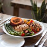 A plate of grilled chicken paired with roasted sweet potatoes, quinoa salad, steamed asparagus, and mixed greens, showcasing healthy side dishes